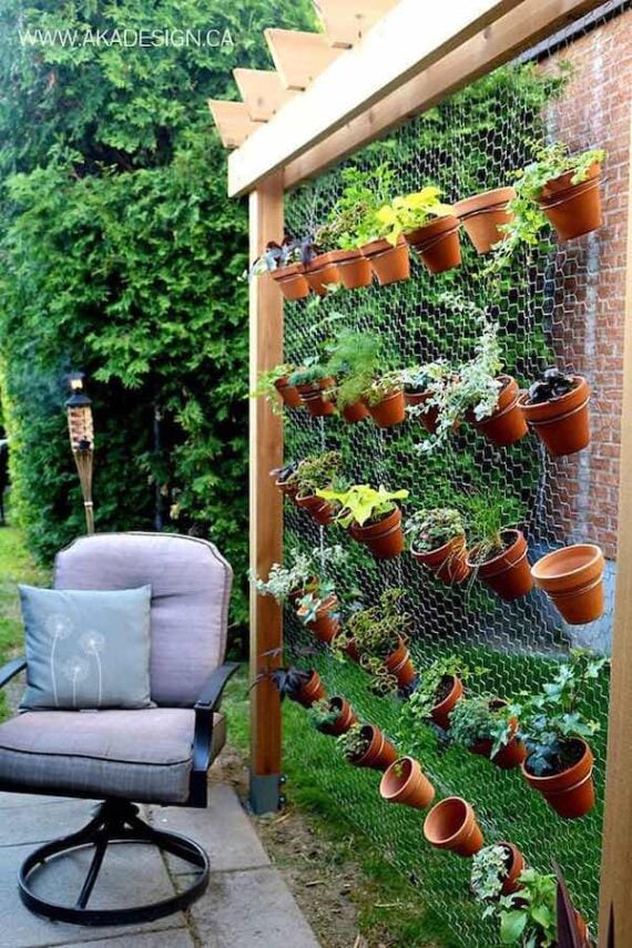 vertical garden with hanging terra cotta pots under a wooden arbor