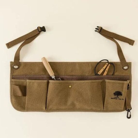 waxed canvas tool belt laid flat on beige background