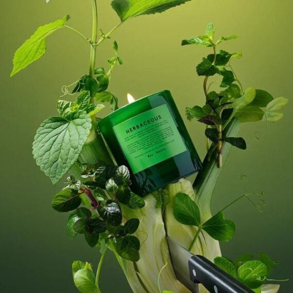 green candle surrounded by herbs and plants