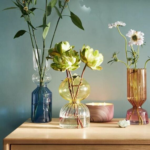 Uniquely shaped flower vases on a table each with flowers